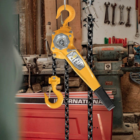 0.75 Ton Manual Lever Chain Hoist with G80 galvanized carbon steel construction, yellow handle, hanging in a workshop.