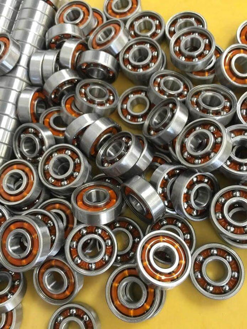 Close-up of 100-Pack Skate Ball Bearings - Nylon Cage - Open showing shiny metal and orange nylon cages.