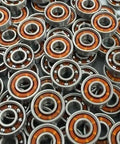 100-Pack Skate Ball Bearings - Nylon Cage - Open, close-up of multiple skateboard ball bearings with orange nylon retainers.