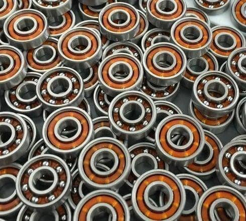 100-Pack Skate Ball Bearings - Nylon Cage - Open, close-up of multiple skateboard ball bearings with orange nylon retainers.