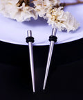 10G Ear Gauges Stretching Kit With 316L Surgical Steel Tapers And Insertion Pins Includes 2 Pieces For Ear Lobe Septum Tongue And Nipple Piercing Smooth Polished Body Jewelry Tools For Safe Easy Stretching At Home, two steel tapers with rubber stoppers on a plate with flowers