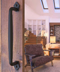 12 Inch Round Rustic Barn Door Handle Black Steel Pull installed on wooden sliding door in modern living room