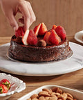 Person placing strawberries on a chocolate cake on a 12 inch white marble lazy susan turntable with aluminum bearing.