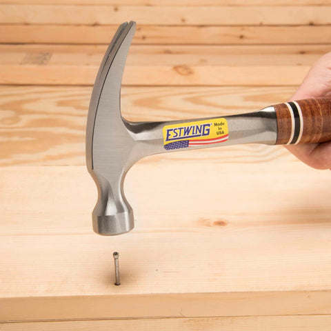 12 Oz Straight Rip Claw Hammer With Smooth Face And Genuine Leather Grip For Framing Carpentry Demolition And Woodworking Made In USA From Forged Steel Pro Grade Hand Tool For Precision Strikes And Durable Performance in use driving a nail into wood.
