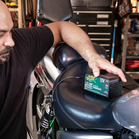 Man using 12V 1.25 Amp Car And Motorcycle Battery Charger And Maintainer With Float Charge For Automotive And ATVs Adaptive Smart Charging with Four Step Charging Program on motorcycle