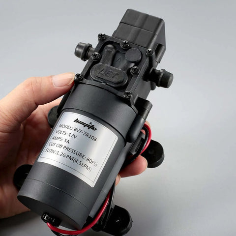 Person holding bayite 12V DC Water Transfer Pump with 2 Hose Clamps 12 Volt Diaphragm Pump Self Priming Sprayer Pump with Pressure Switch
