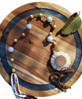 16 inch large lazy susan turntable made from acacia wood and resin with decorative accessories and leaves.