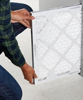 Person installing Six pack MERV 8 furnace air filters fit standard 16x20x1 slots, trapping dust, pollen and lint to improve indoor air quality.