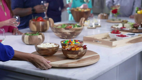 20 inch acacia wood lazy susan turntable designed for tables and counters, featuring bowls filled with snacks and salads.
