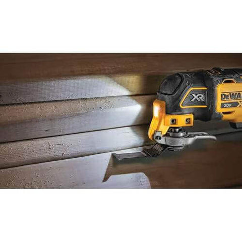 20V Max XR Oscillating Tool Kit with Blades and Charger Included cutting wood, showing LED light and dual grip variable speed trigger