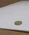 Virgin PTFE Sheet One Eighth Inch Thick, Twelve By Forty Eight Inches for gaskets, shown with coin for scale, demonstrating thickness and size.