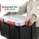 Person lifting Two Pack Heavy Duty Plastic Storage Bins Thirteen Point Five Gallon Gasket Totes With Airtight Silicone Seals Rock Solid for garage.