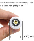 23mm diameter brass shower door wheels with nylon rollers and stainless steel screws held in hand displaying size
