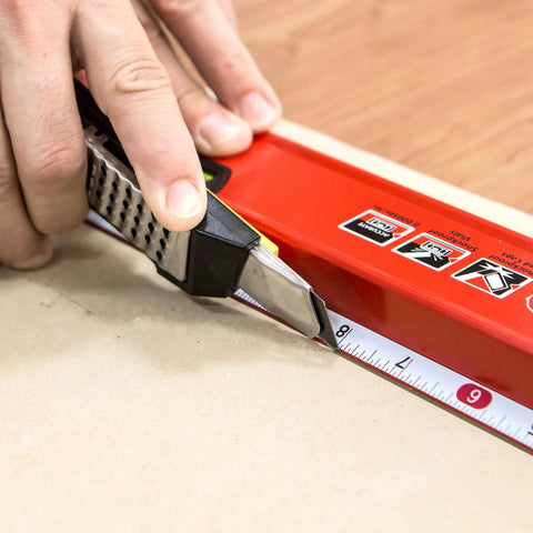 Hand using a 24 inch box level with three durable acrylic vials, precise 1/16 inch ruler, wall grip, and hand calibrated straightedge.