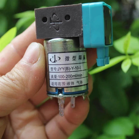 Hand holding 24V Mini Diaphragm Pump, model JYY(B)-Y-10-I with labels, compact design for lab analysis and scientific DIY projects