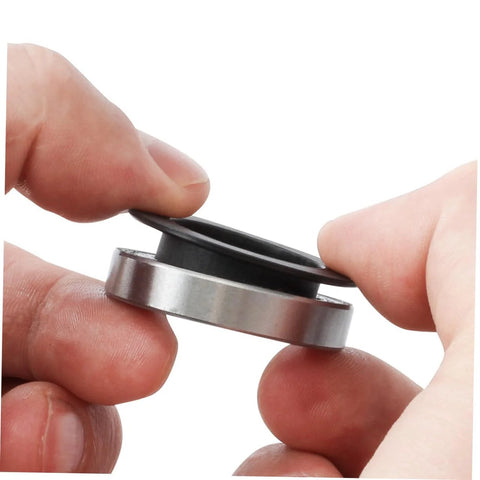 Close-up of hands holding Two Pack Black Axle Protection Covers for Bike Bearings Dust Covers, showing installation.