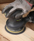 280W Orbital Sander 13000 RPM With Dust Collection And 15 Discs in use on wooden surface with ergonomic grip and dust bag.