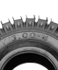 Close-up of 3.00-4 260 x 85 tire with knobby tread for scooters and go-karts, showing TR87 valve stem.