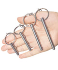 Hand holding four sets quarter inch diameter single ball quick release pins made from 316 stainless steel with lanyard and screws.
