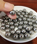 Hand holding 0.3mm solid 316L stainless steel ball over a dish of 100Pcs 0.3mm Solid 316L Stainless Steel Ball - Smooth Beads Round Balls.