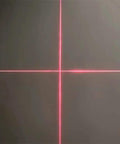 Red crosshair laser alignment projector projecting vertical and horizontal lines on a dark surface