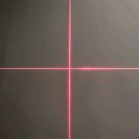 Red crosshair laser alignment projector projecting vertical and horizontal lines on a dark surface