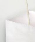 Close-up of Medium White Kraft Paper Bags With Handles 8x4.75x10 Inches Bulk Pack Of 100 for birthday party favors and wedding goody bags