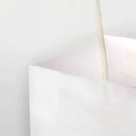 Close-up of Medium White Kraft Paper Bags With Handles 8x4.75x10 Inches Bulk Pack Of 100 for birthday party favors and wedding goody bags