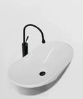 Bathroom Sink Modern Minimalist Art Basin Hotel Bathroom Ceramic Above Counter Basin with black faucet and smooth curves.