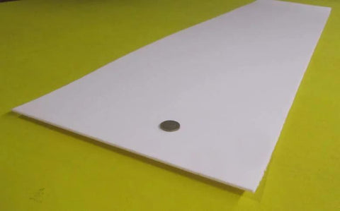 Virgin PTFE Sheet One Eighth Inch Thick, Twelve By Forty Eight Inches, shown on yellow surface, coin for scale.