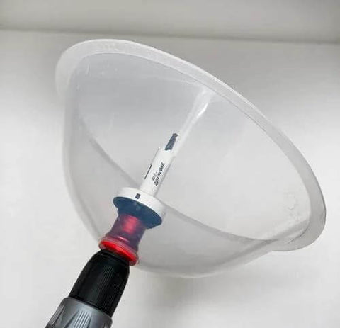 Close-up of clear collapsible dust bowl accessory for hole saws mounted on a drill with arbor