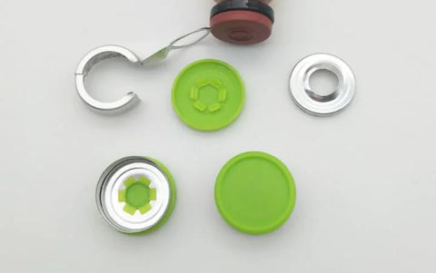 Top-down view of several empty 10ml borosilicate glass lab vial components with green caps and aluminum flip-off closures