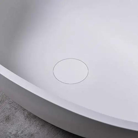 Close-up of the interior of a Real Deal White Oval Vessel Sink Built Tough From Dense Artificial Stone with drain hole.