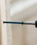 Close-up of 1/4 Inch Hex Washer Head Concrete Screw For Masonry, Brick And Block being installed with a drill into wood and concrete