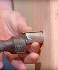 Southwire Smart Shield nail guard being installed on a wooden stud with hammer