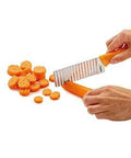 ZYLISS crinkle-cut knife side view with orange handle and stainless blade cutting carrots into crinkle slices
