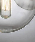 Close-up of Sick Industrial Pendant Light, Round Glass Globe Hanging Lamp showing the clear glass globe and vintage bulb.