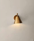 Handcrafted Brass Wall Sconce with Finial Vintage Hardwired Light mounted on a wall, featuring a cone-shaped brass shade.