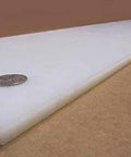Side view of Tough As Nails White UHMW Polyethylene Sheet Five Sixteenth Inch Thick Twelve By Forty Eight Inches on brown surface