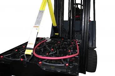 Industrial forklift battery lifting sling with yellow strap and white tag mounted on forklift battery area.