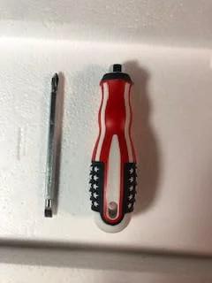 Red and blue star-patterned screwdriver handle with metal bit on white surface