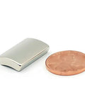 NdFeB arc-segment magnet, silver, with a penny for scale