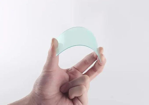 Slick Welding Helmet Cover Lens Replacement Kit Packs Twenty Heavy Duty Polycarbonate Filter Pads For Inside And Outside Use To Keep Your Welding Mask Visor Crack Free And Pristine On The Shop Floor - clear polycarbonate lens held in hand.