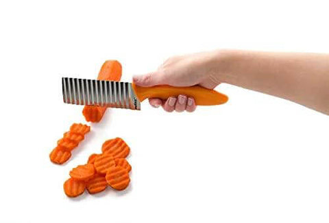 Crinkle cut knife with orange handle and stainless steel blade slicing carrot slices.