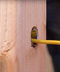Southwire Smart Shield wire protection guard: wooden stud with yellow electrical wire passing through a drilled hole
