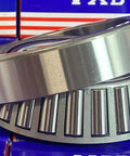 Close-up of 33117 Tapered Roller Wheel Bearing 85x140x41 showing chrome steel construction on a blue background.
