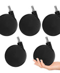 5 black 4 inch extra large chair wheels resting on a surface, showcasing grip ring casters for wood and carpet, hand for scale.