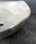 Close-up of bathroom sink marble ceramic sink showing smooth edges and drain hole for hotel bathroom washbasin.