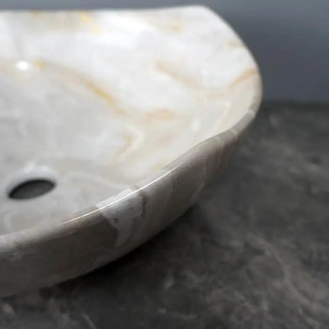 Close-up of bathroom sink marble ceramic sink showing smooth edges and drain hole for hotel bathroom washbasin.