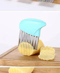 Crinkle-cut veggie chopper with blue handle and stainless-steel blade; ridged potato slices on cutting board.